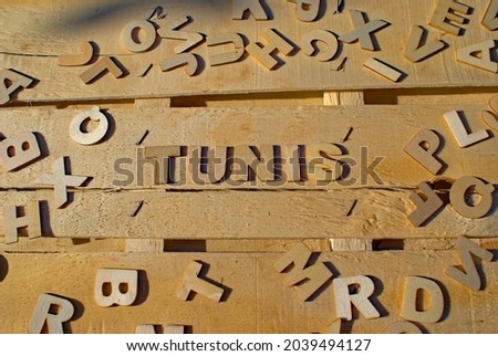Word Tunis made of wooden block letters on the background of other letters above the composition of the surface of the wooden board