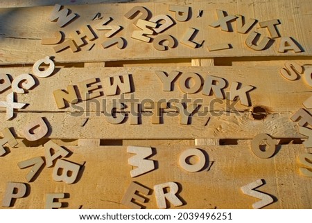 Word New York City made of wooden block letters on the background of other letters above the composition of the surface of the wooden board
