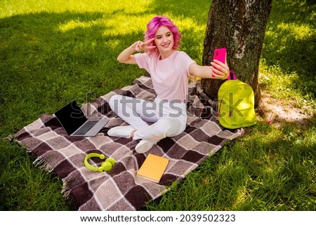 Full length photo of sweet millennial pink hairdo lady sit do selfie wear t-shirt trousers sneakers in park alone
