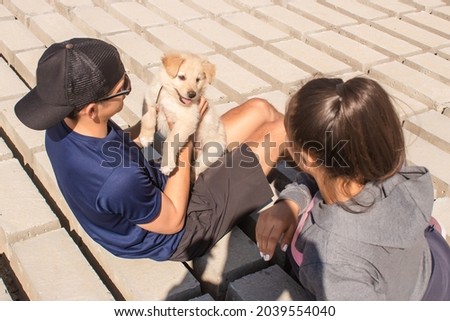 Couple sitting with their puppy, playing on the shore.