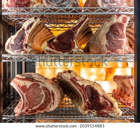 Beef steak in dry aged meat aging cabinet. Barbecue steak on fridge in delicious gourmet restaurant. Dry aging meat in cold storage. Dry-aged cuts of raw meat, aged beef for steaks Royalty-Free Stock Photo #2039554883