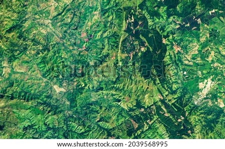Nature pattern on satellite photo, topography. Aerial view of green Earth surface as abstract texture background. Forest or jungle taken from space in summer. Elements of this image furnished by NASA. Royalty-Free Stock Photo #2039568995