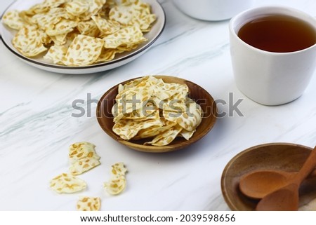 Keripik Tempe or Tempeh Crackers or tempeh chips on ceramic bowl with cup of tea. Tea and snack time. Selective focus, copy space. Indonesian snack.