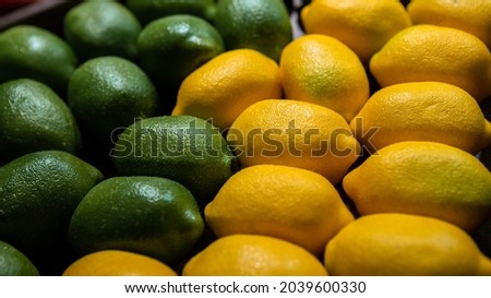 Lime and lemons background on market counter. Fresh organic lemon on a local farmer food supermarket. Close up view of fruits in the cardboard box on the grocery shelf.