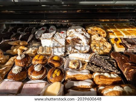 Breakfast of spanish biscuits, sweet pastries, puff pastry, powdered sugar and baked apples dessert. Typical sweets confections consumed in the window of a pastry shop at Spain. Royalty-Free Stock Photo #2039600648