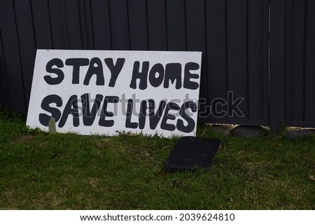 A sign leaning against a fence with a Coronavirus related message