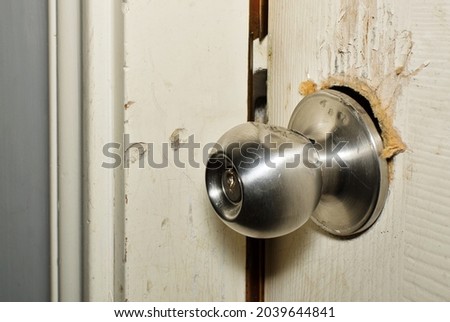 Broken modern doorknob closeup with signs of forced entry, criminal activity and door slightly open. Breaking and entering concept.