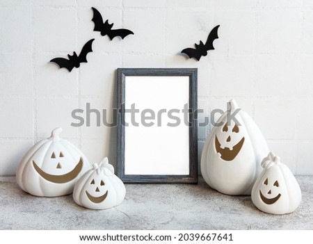 Mock up  frame with Jack o Lantern and pumpkin decor on a table. Halloween concept. Poster frame against a white wall with bats.