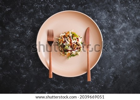 big plate with small amount of salad in the centre, concept of dieting and calorie restrictions Royalty-Free Stock Photo #2039669051