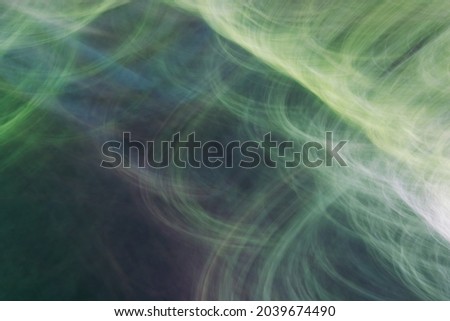 Drawing with light, depicting rays, circles, thin lines, glare. Abstract background in shades of green. Photo effect.