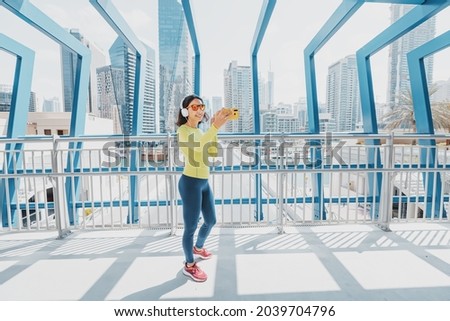 Woman in bright sportswear takes a selfie photo for her social networks while jogging through the streets of the city