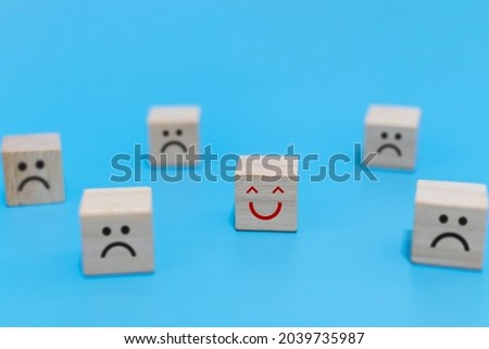 Happy and Unhappy emotion. happy smile face with sad face on wooden cube on blue background, positive think, social issues, customer satisfaction ,positive attitude, optimism and pessimism concept