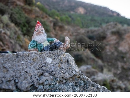 gnome lying on a stone and mountains in the background with vegetation