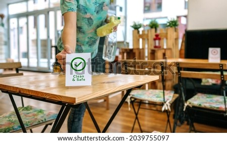 Unrecognizable waitress placing Clean and Safe sign on coffee shop table