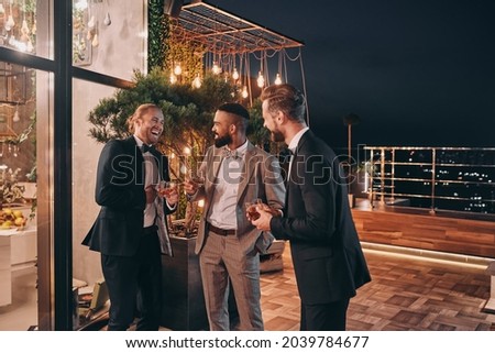 Three well-dressed men drinking whiskey and communicating while spending time on party Royalty-Free Stock Photo #2039784677