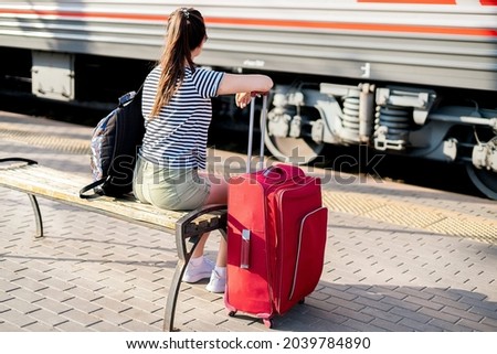 female person sitting on the train station and waiting for the trip