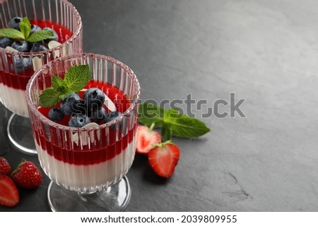Delicious panna cotta with fruit coulis and fresh berries on dark grey table. Space for text