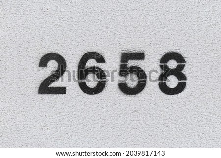 Black Number 2658 on the white wall. Spray paint. Number two thousand six hundred fifty eight.