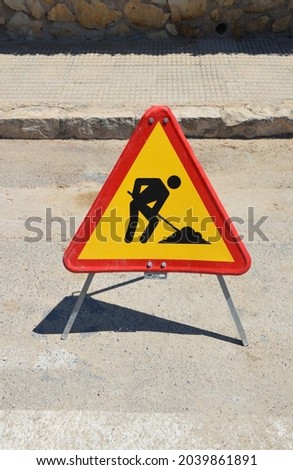 Triangle road work sign on street near sidewalk