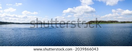 panoramic landscape with lake, blue sky and clouds