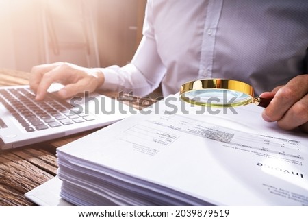 Investigating Corporate Tax Fraud. Commercial Auditor Using Magnifying Electronic Royalty-Free Stock Photo #2039879519