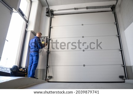 Garage Door Installation And Repair At Home. Contractor Man In House Royalty-Free Stock Photo #2039879741