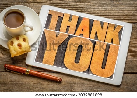 thank you - word abstract in vintage letterpress wood type on a digital tablet with coffee and cookie