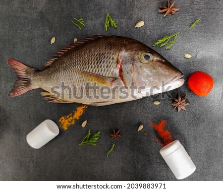 Fresh Emperor Fish decorated with herbs and vegetables on a black pad.White Background Royalty-Free Stock Photo #2039883971