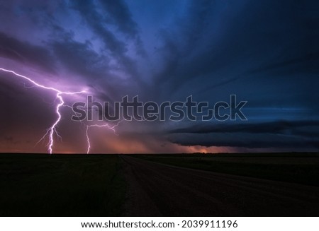 Magnificent lightning bolts in the distance illuminate the night sky cutting through dark storm clouds