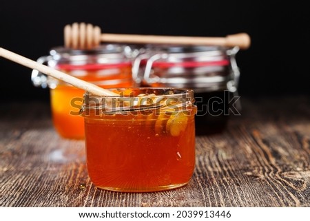 a spoon for honey together with high-quality bee honey, an old table on which there is a healthy and sweet bee honey and a homemade wooden spoon that allows you to transfer and pour honey