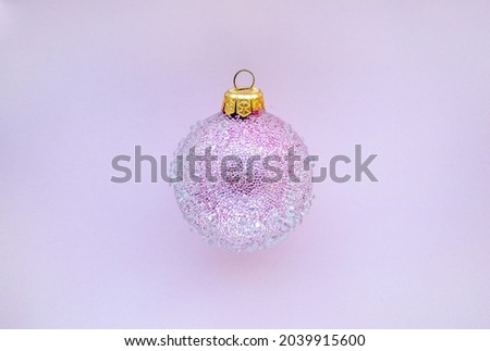 Pink christmas ball with some bumps on a pink background. Minimal Christmas design, place for text