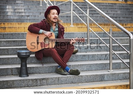 Joyful man with dreadlocks playing music outdoors Royalty-Free Stock Photo #2039932571