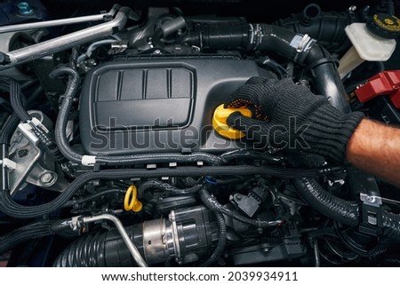 Worker removing oil filler cap of engine Royalty-Free Stock Photo #2039934911