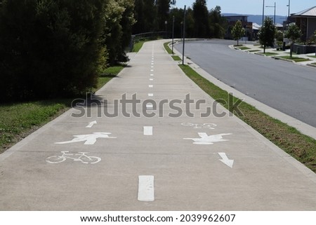 White cement suburban footpath, shared between pedestrian and bicycle riders, empty on a sunny winter day.