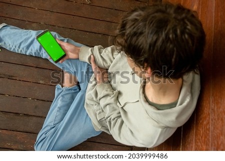 Hands of teenager boy holding phone with green screen, adolescent boy using phone, modern digital technologies