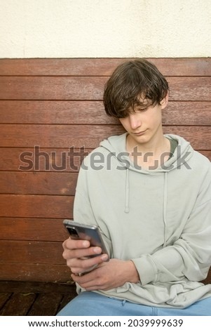 teenager boy holding phone , adolescent boy using phone, modern digital technologies