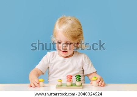 A 3-year-old child is playing at a table with a colorful education toy on blue background