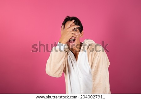 Young and handsome man in pajamas on a pink background. Emotions of guys.