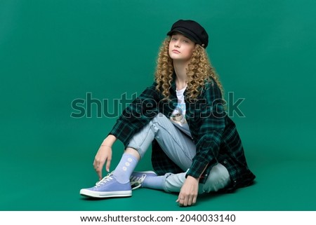 Pretty teen girl in trendy outfit sitting on floor