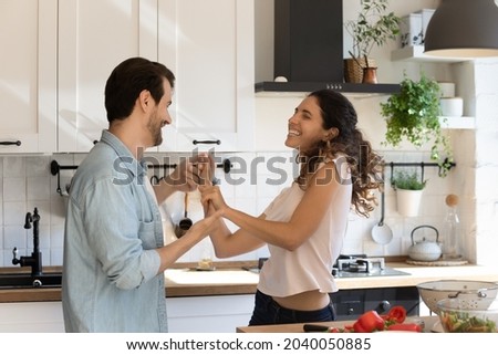 Couple in love hold hands dance in kitchen spend carefree weekend at home distracted from cooking feels happy. Homeowners celebrate first dinner at new house, having romantic date, lifestyle concept Royalty-Free Stock Photo #2040050885