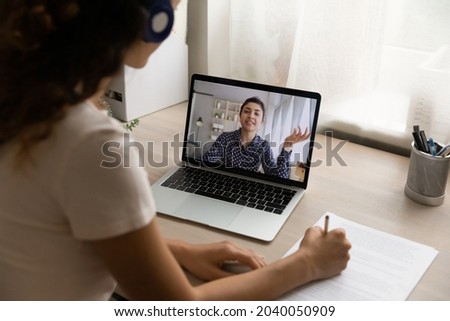 Indian woman participate in videoconference, laptop screen view over female shoulder. Businesswomen negotiating remotely, tutoring and online counselling, e-study process via video call event concept Royalty-Free Stock Photo #2040050909