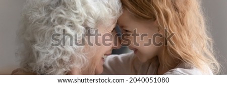 Horizontal banner photo sincere bonding older senior grandmother touching foreheads with smiling adorable 7s grandchild, enjoying sweet tender moment together at home, good family relations concept. Royalty-Free Stock Photo #2040051080