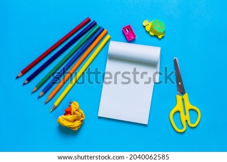 Blank notebook and school stationery on blue background.