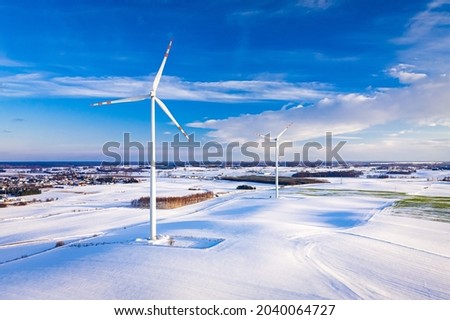 Wind turbine on snowy field. Alternative energy in winter. Aerial view of nature in Poland, Europe Royalty-Free Stock Photo #2040064727
