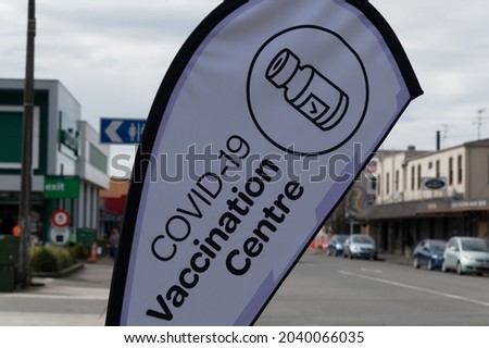 A Covid-19 vaccination centre announces its presence in a New Zealand town with a pavement flag Royalty-Free Stock Photo #2040066035