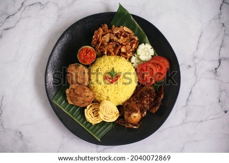 Nasi Kuning is an Indonesian Food which means Yellow Rice. The rice is served with a bunch of side dishes. Nasi Kuning is commonly served as breakfast or lunch.  Royalty-Free Stock Photo #2040072869