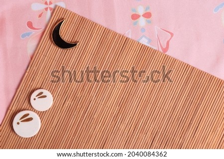 Japanese backgound. chopstick stands with the image of a moon rabbit on the background of a bamboo mat and pink fabric in a traditional style. The concept of the mid-autumn