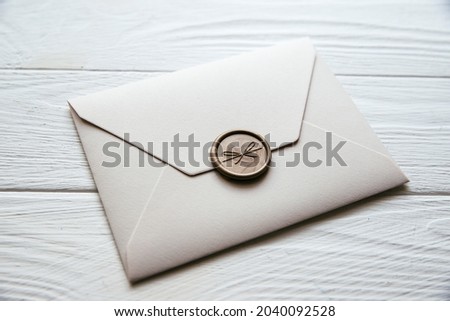Beige envelope on a white wooden table background. Invitation envelope for wedding, holiday, birthday, party invitation, Christmas envelope. Cose up photo. Family tradition concept.
