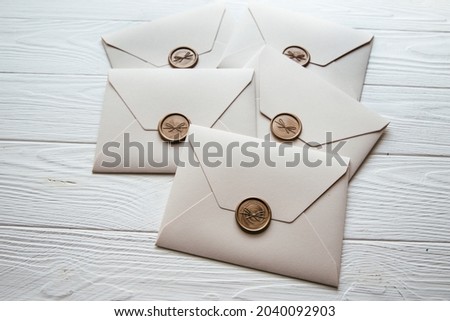 Five beige envelopes on a white wooden table background. Invitation envelope for wedding, holiday, birthday, party invitation, Christmas envelope. Cose up photo. Family tradition concept.