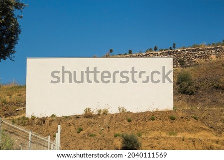 A white colored blank billboard outdoors, outdoor advertising, public information board on land with blue sky